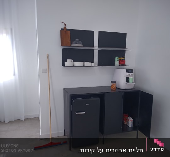 מטאטא עומד ליד ארון שחור עם מדפים